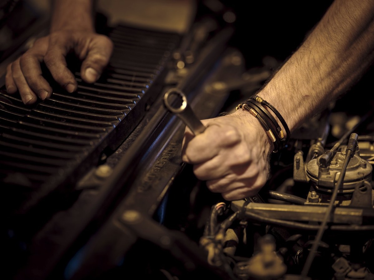 Mains d'un mécanicien serrant une pièce du moteur avec une clé