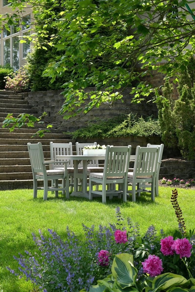 Table et chaises sur une pelouse entourée de murets végétalisés
